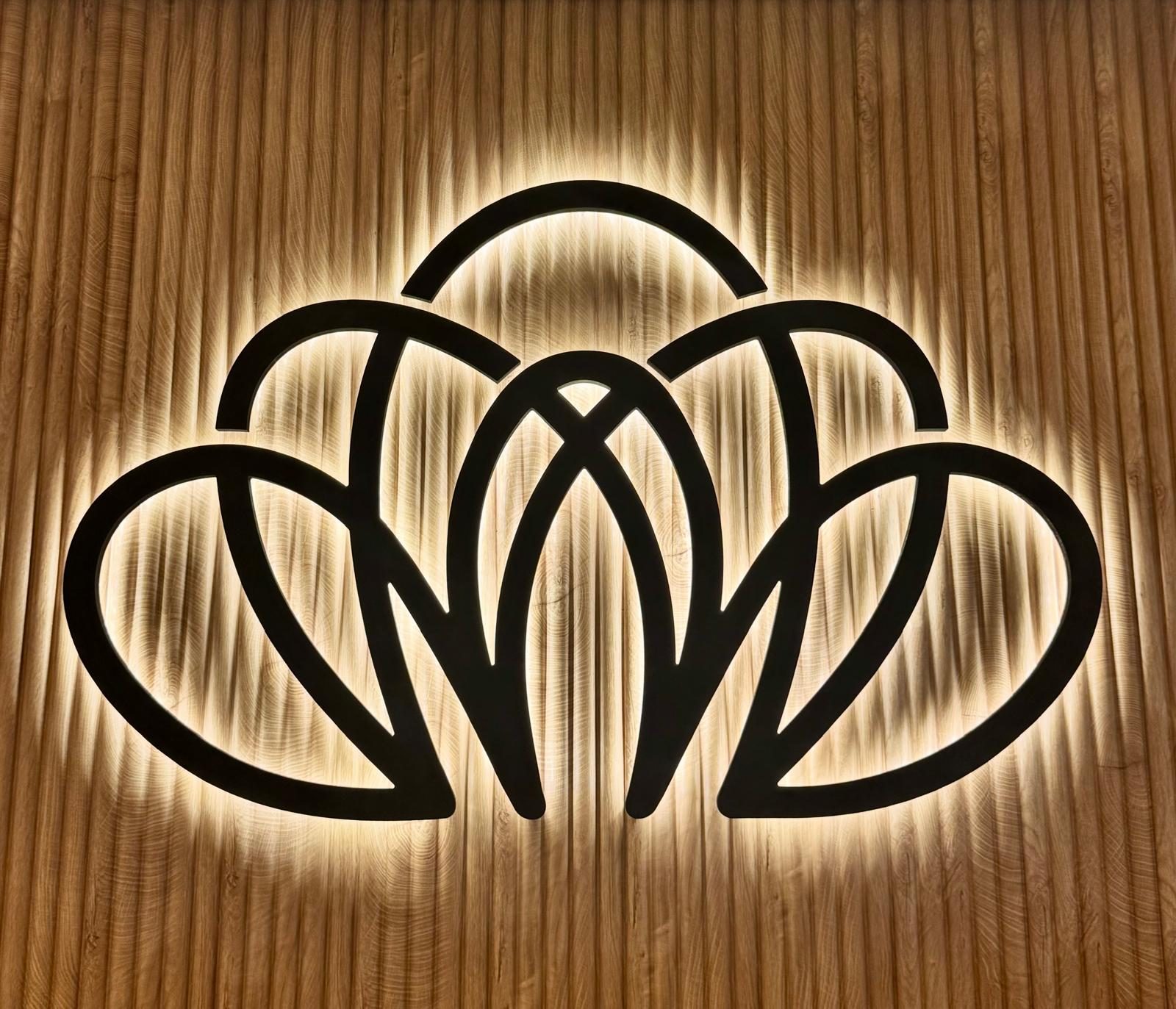 Backlit Rejuvaline lotus logo on a wood-slat wall